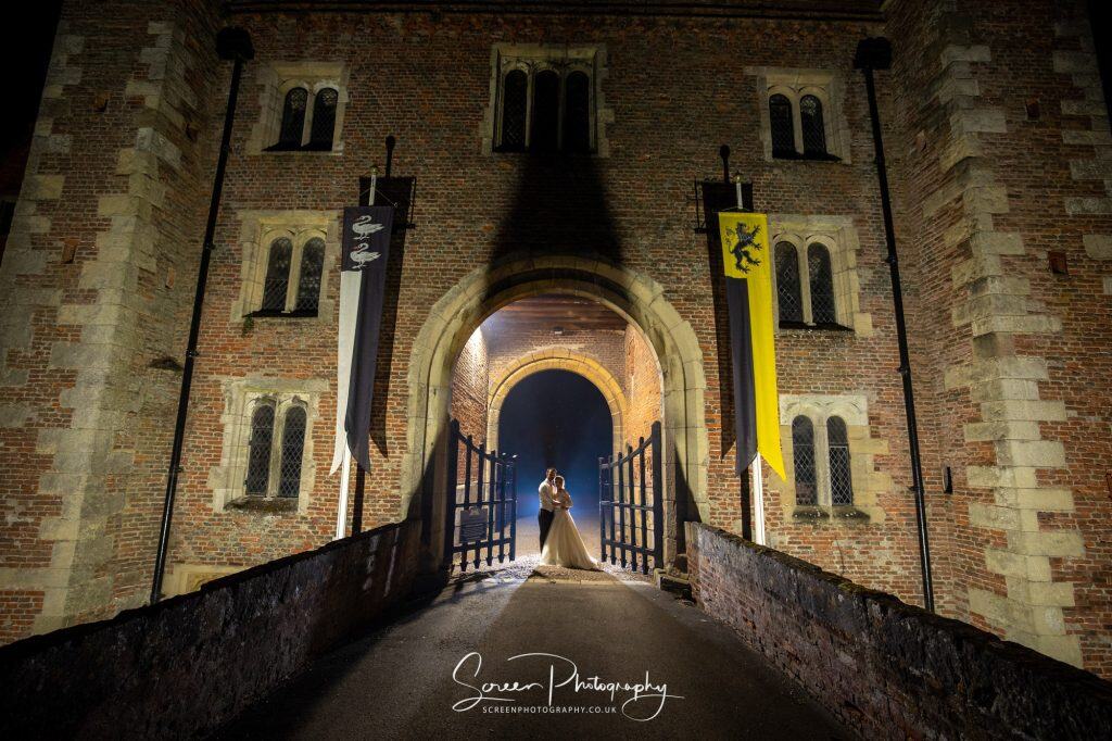 hodsock priory wedding photography bride groom on draw bridge with blue gel behind them at night